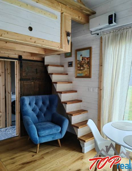 Interior of a family house with a blue armchair, wooden staircase, and floor with a wooden decor.