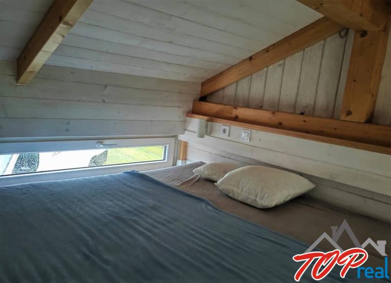 Attic bedroom with wooden beams and a small window in a family house.