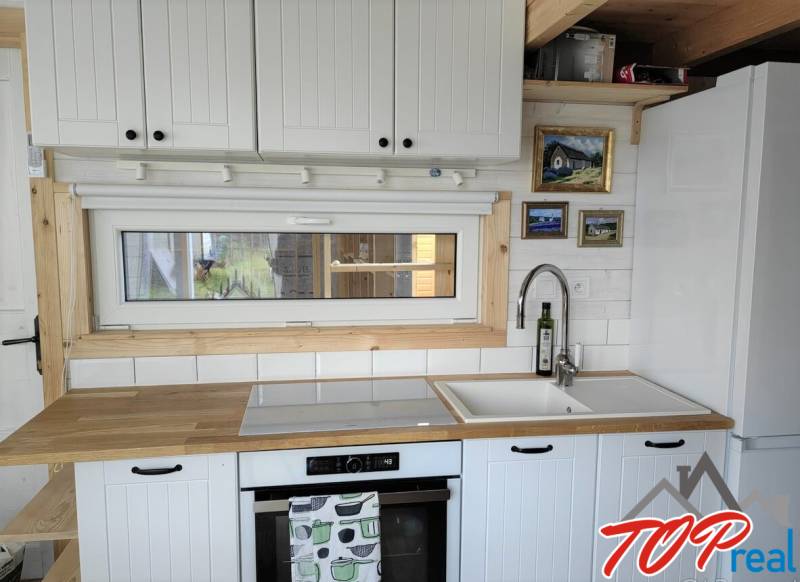 A kitchen in a family house with wooden decor, white cabinets, and a window.