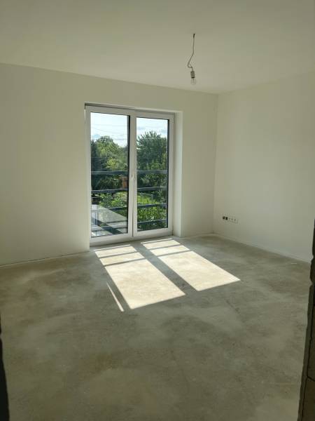 A spacious room with a large window in a family house, concrete floor.