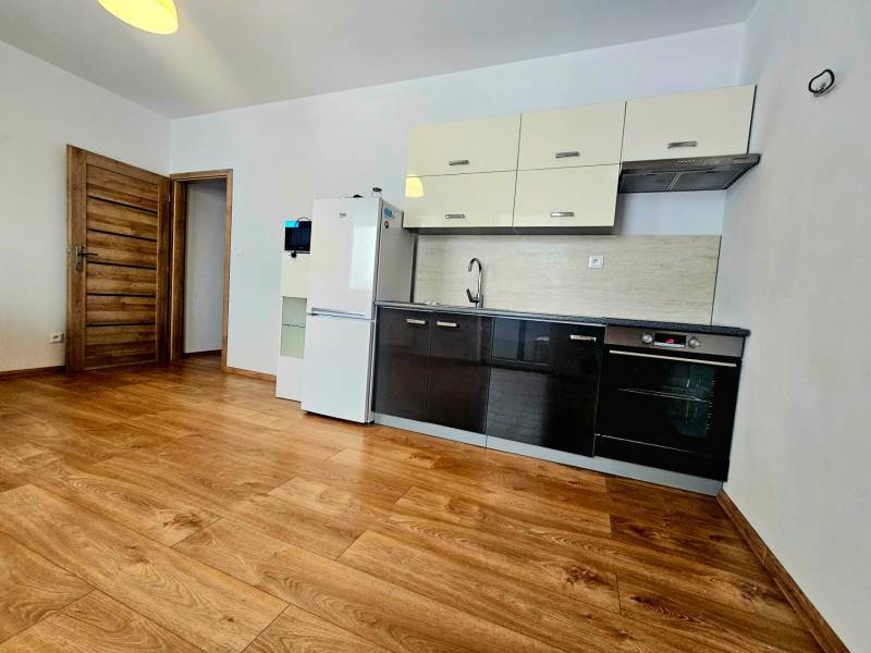 A kitchen in a 2-room apartment with a wooden decor floor and furnishings.