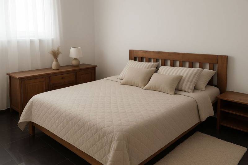 A bedroom with wooden furniture, a bed, and decorative pillows, muted colors.