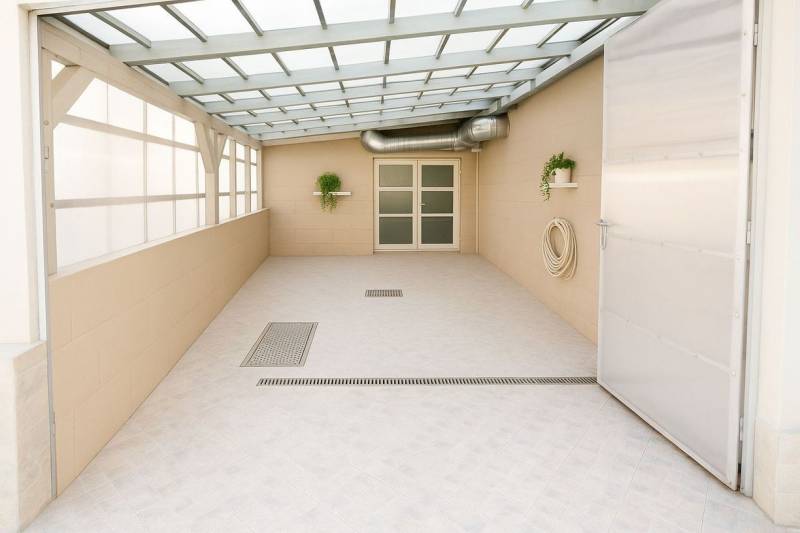 Covered terrace with plants, doors, and drainage in the building.