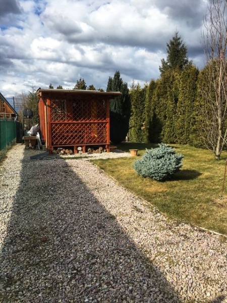 Wooden cottage in Kráľová nad Váhom with a landscaped garden and a bush.
