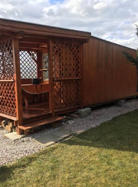 A wooden cottage in Kráľová nad Váhom with a small raised terrace and a lawn.
