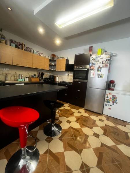A kitchen with a decorative floor, kitchen cabinets, and appliances in a family house.