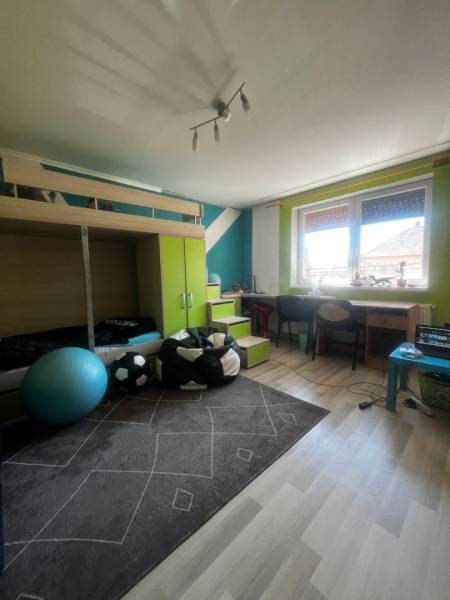 Children's room in a family house with a bunk bed, a desk, and a floor with a wooden decor.