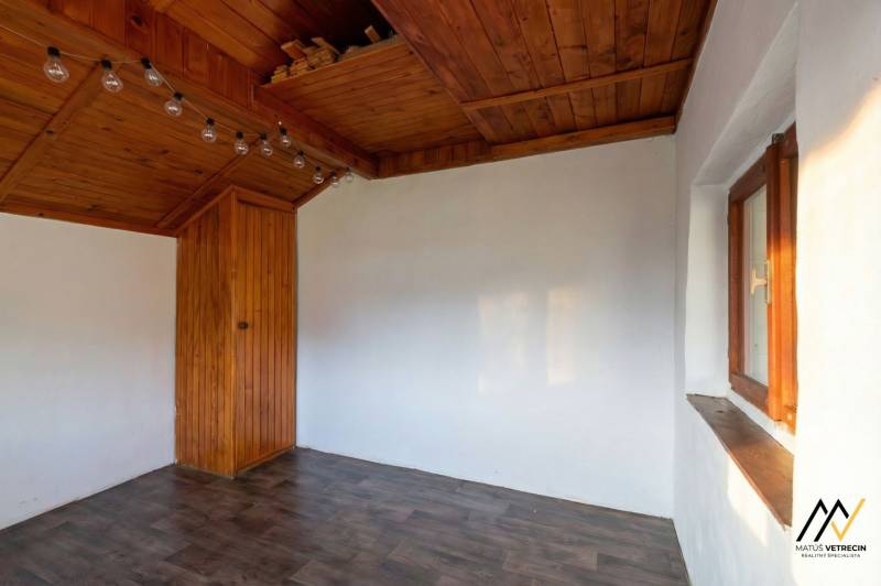 The interior of a cabin with white walls, a wooden ceiling, and a floor with a wooden decor.