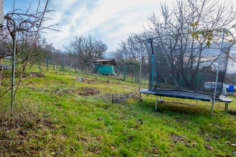 A trampoline and a cottage in the garden in Prešov, surrounded by trees and grass.