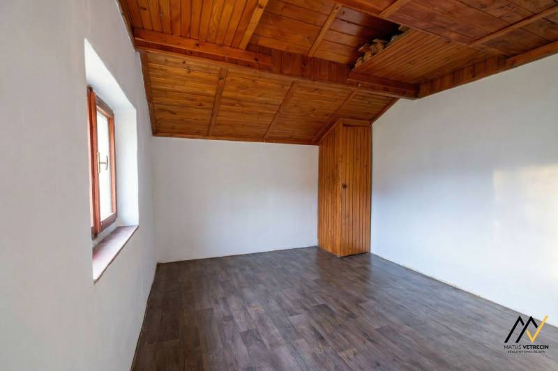 A room in a cottage with a wooden ceiling and a floor with a wooden decor.