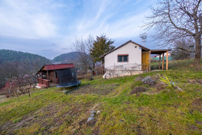 A cottage in Prešov surrounded by trees, with a view of the hills and a trampoline in the garden.