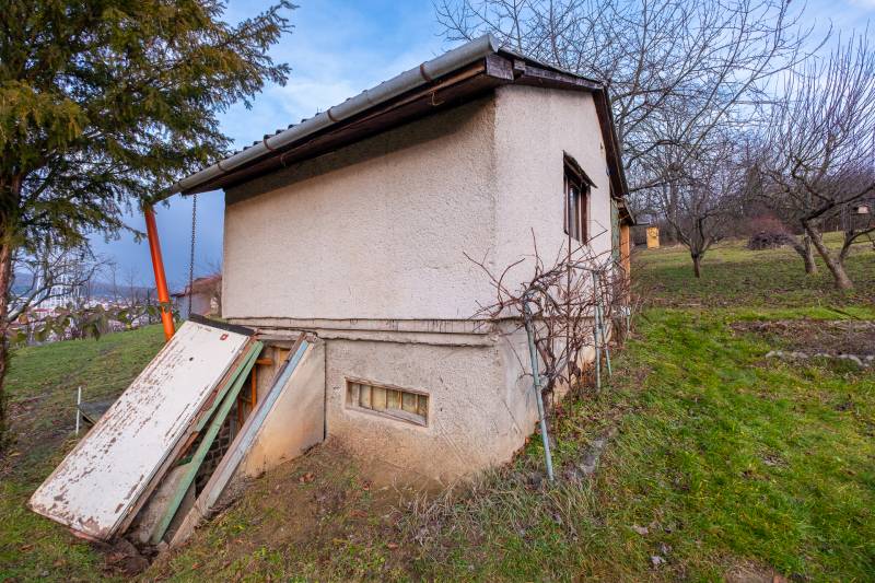 A cottage in Prešov surrounded by greenery, with simple plastering and an exterior entrance.