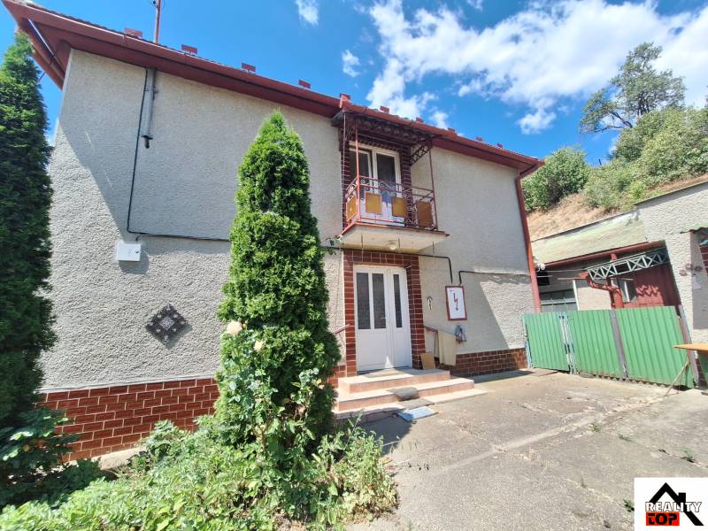 A family house in Tachtoch with a gate, terrace, balcony, and surroundings with greenery.