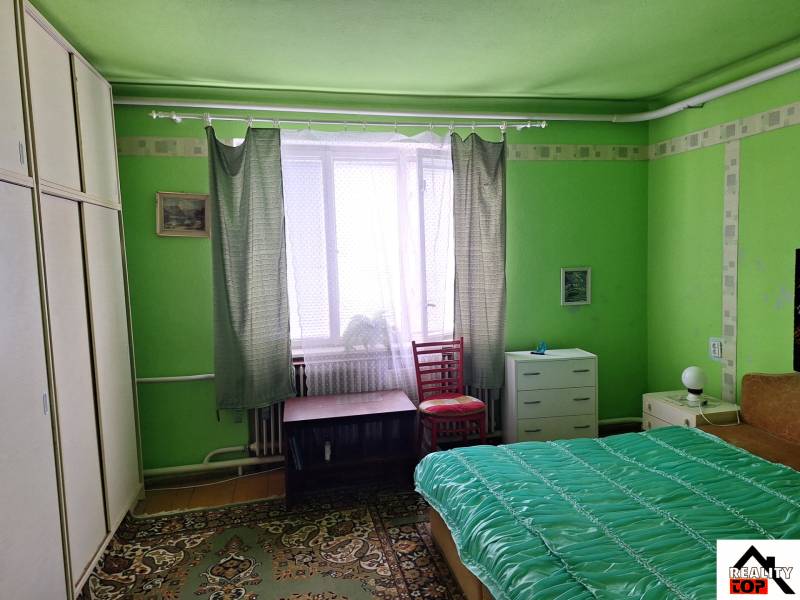 Green room in a family house with a bed, wardrobe, and carpet.