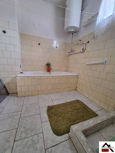 Bathroom in a family house with a bathtub and tiled walls.