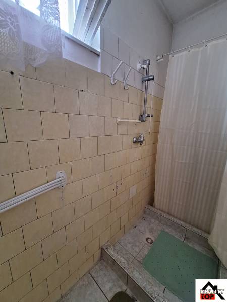 A bathroom in a family house with ceramic tiles and a curtain above the shower stall.