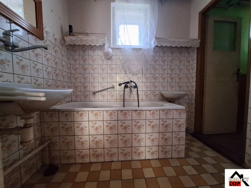 Bathroom in a family house with floral patterned tiles and a bathtub.