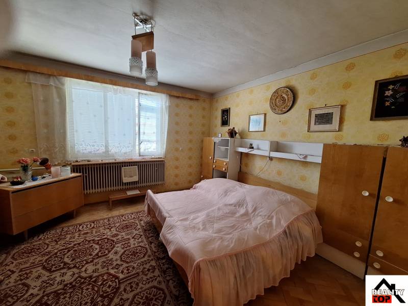 A bedroom in a family house with retro furniture, a carpet, and yellow wallpaper.