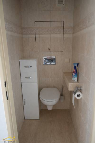A toilet in light tiles in a 3-room apartment with storage space.
