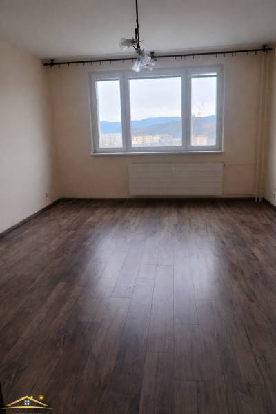 A room with a large window, a floor with a wooden decor in a 3-room apartment.