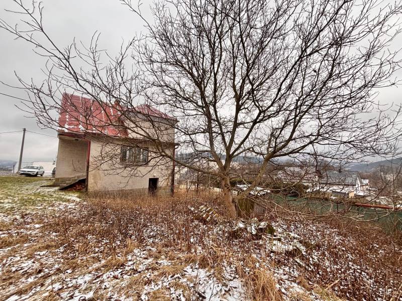 A family house in Poľana in Skalité without foliage, with the surroundings covered in light snow.
