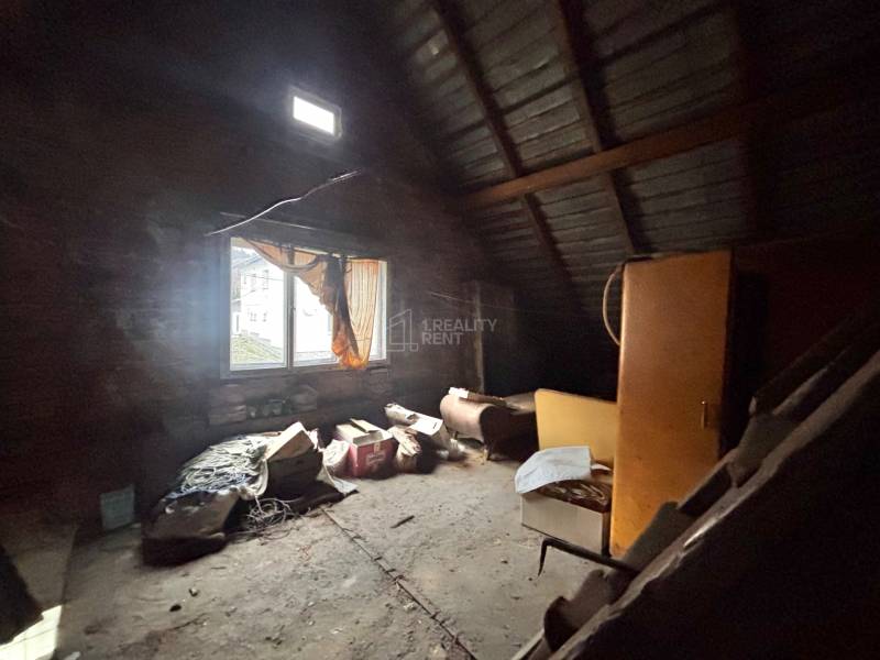 Attic room with a window in a family house full of old items and furniture.