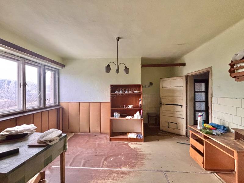 A room in a family house with furniture, shelves, and a large window.