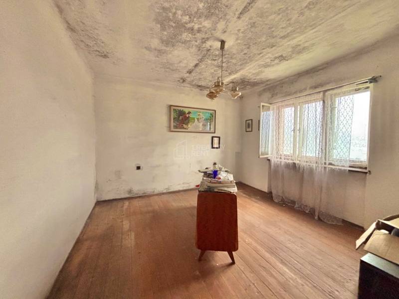 A room in a family house with simple furniture and a wooden-patterned floor.
