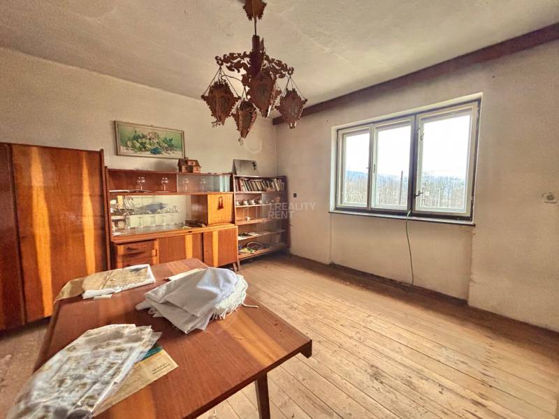 A room in a family house with wooden decor, vintage furniture, a chandelier, and a large window.