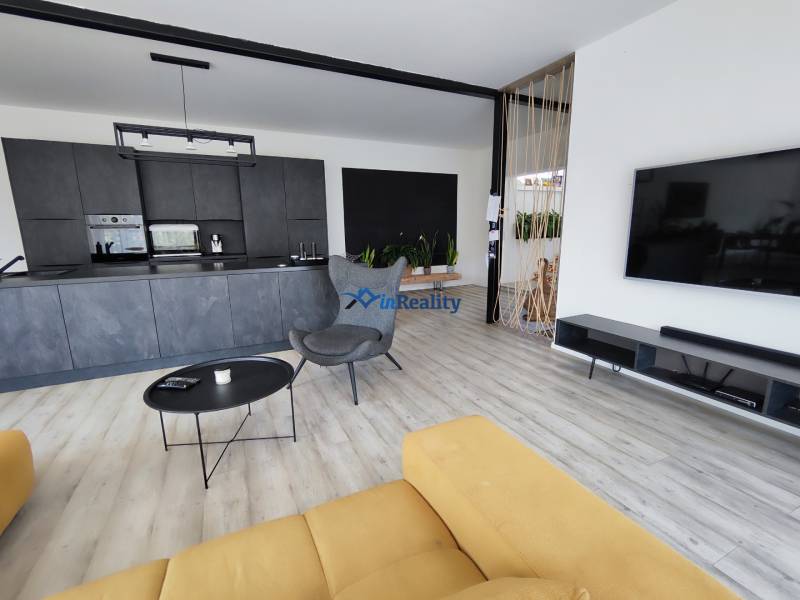 Living room with kitchen in a family house, wooden decor flooring and a yellow sofa.