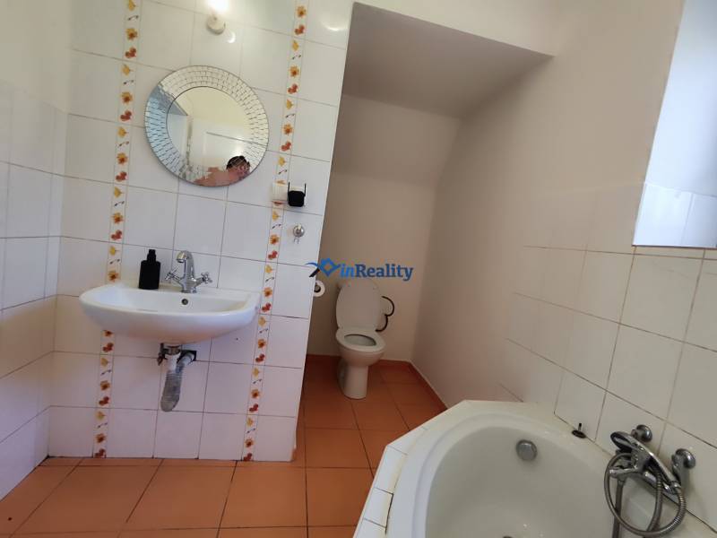 A bathroom in a family house with a round mirror, toilet, and bathtub.