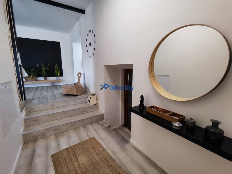 Interior of a family house with a wooden decor floor, a round mirror, and houseplants.