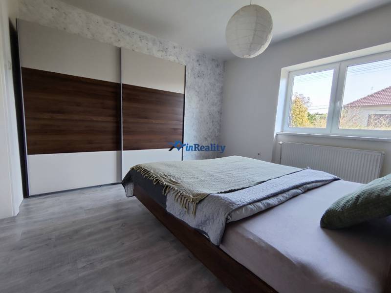 A bedroom in a family house with a large wardrobe, a bed, and a floor with a wooden decor.