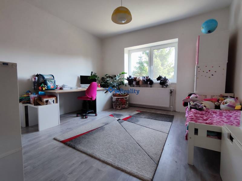 Children's room in a family house with a wooden decor floor, a desk, and toys.