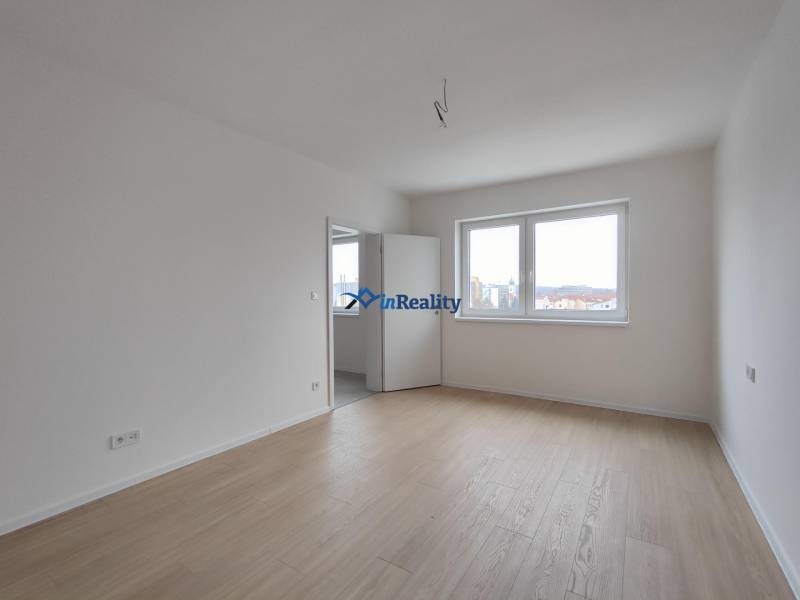 Bright room with wood-patterned flooring in a 2-room apartment.
