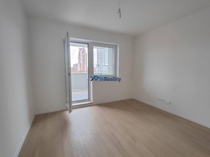 A room in a 2-room apartment with a wooden decor floor and a balcony.