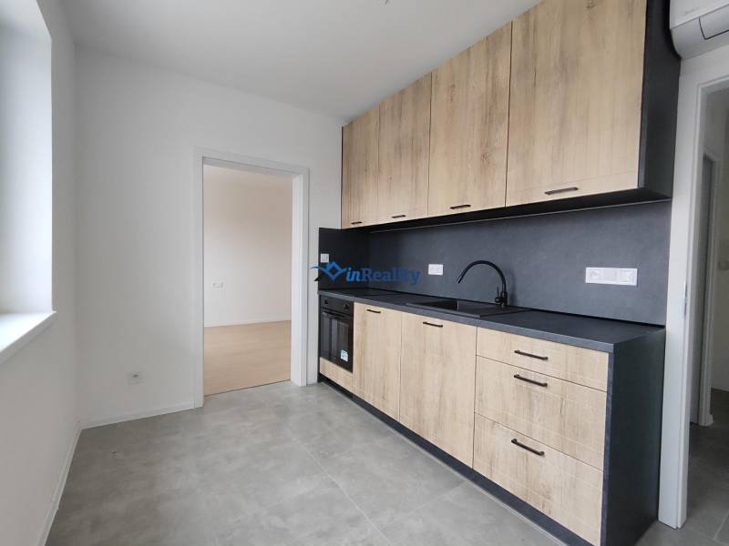 A kitchen in a 2-room apartment with a wooden decor floor and ceramic tiles.