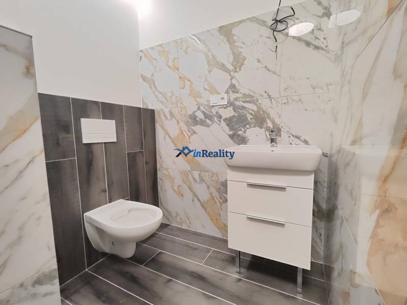 Bathroom in a 2-room apartment with a storage cabinet and a toilet, tiling with a marble design.