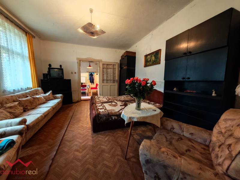 Living room in a family house with sofas, TV, and wood-patterned flooring.