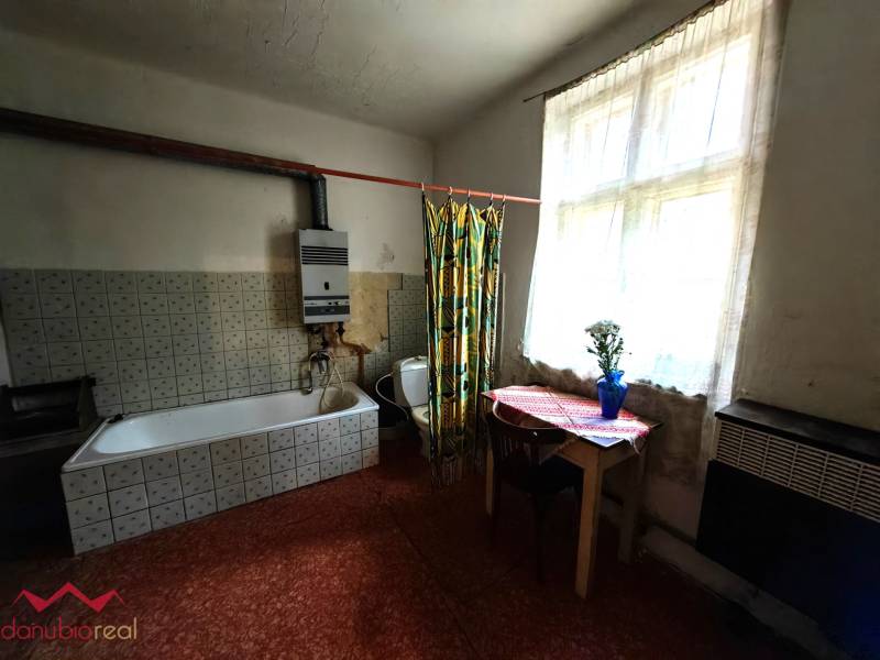 A bathroom in a family house with an older bathtub and a small table by the window.