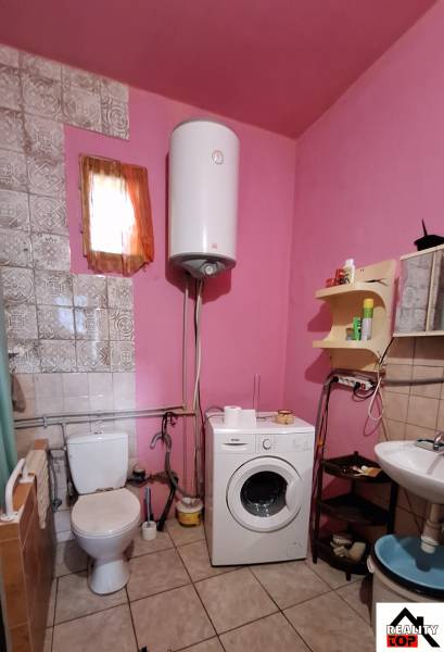 A bathroom in a family house with a washing machine, toilet, and pink walls.