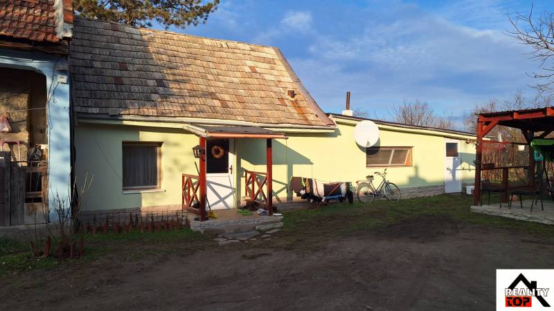A family house in Rapovce with a veranda, a satellite dish, and a bicycle leaning against the wall.