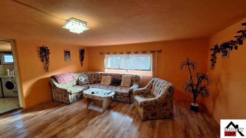 A living room in a family house with orange walls and a wooden decor floor.