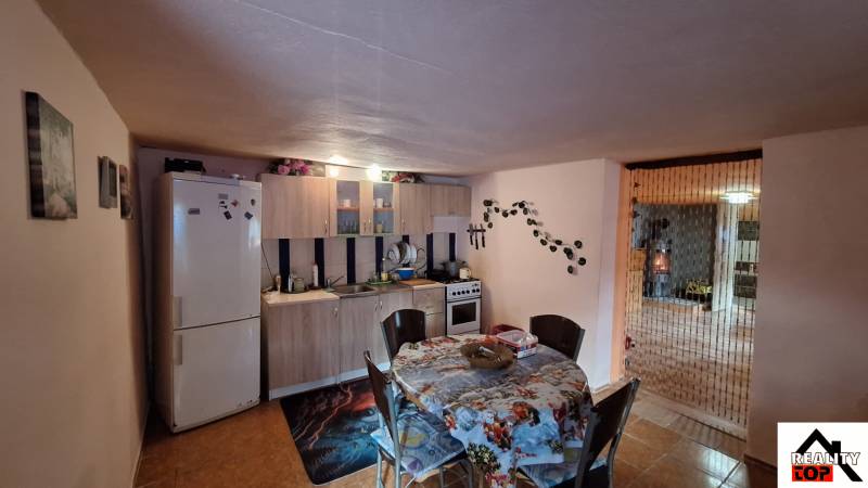 A kitchen in a family house with a dining table, kitchen counter, and refrigerator.
