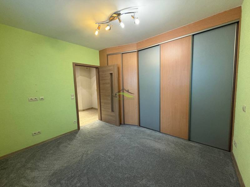 A room in a three-room apartment with a colored wall, a wardrobe, and bright lighting.