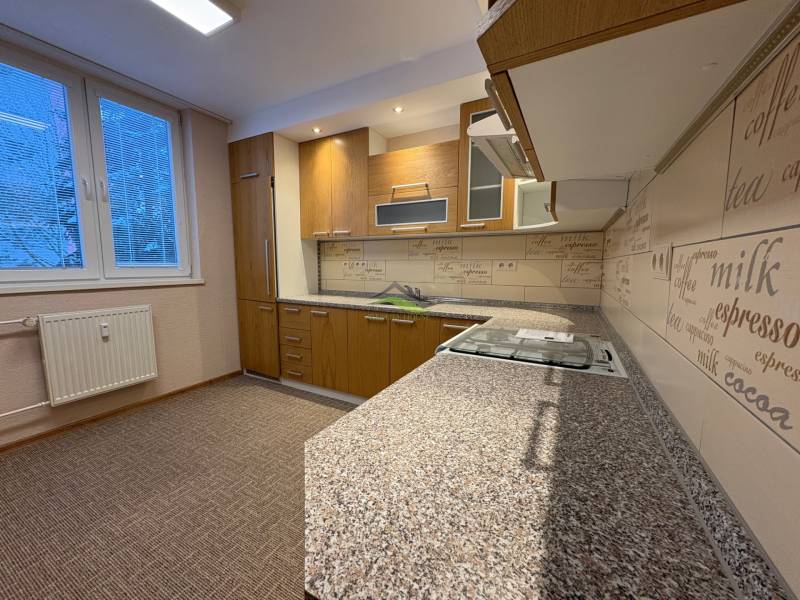 A kitchen in a 3-room apartment with a wooden decor floor and a modern kitchen unit.