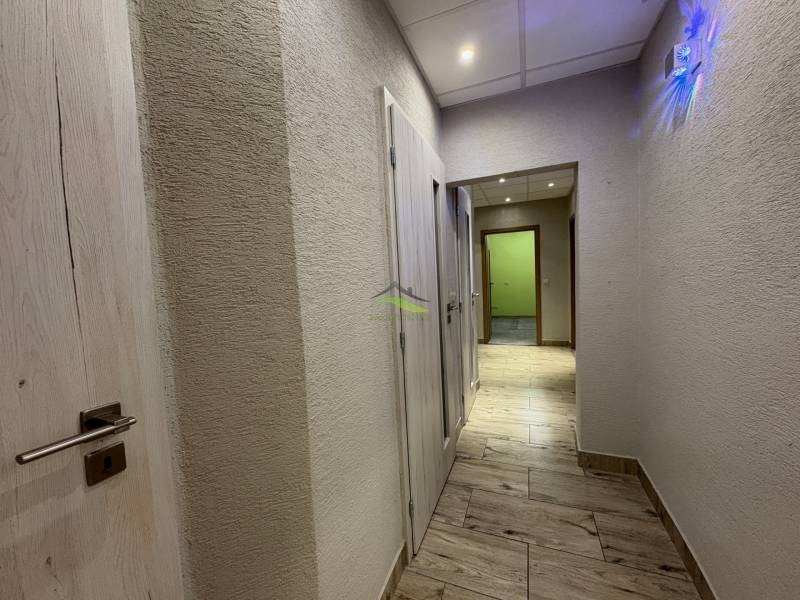The hallway of a 3-room apartment with a wooden decor floor and walls with a subtle texture.