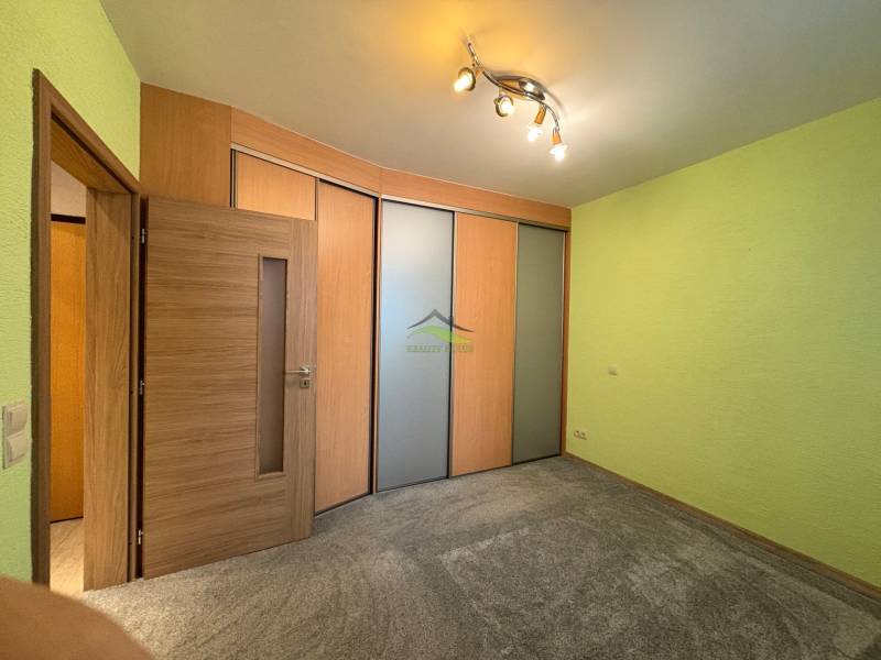 A room in a 3-room apartment with sliding doors, green walls, and spot lighting.