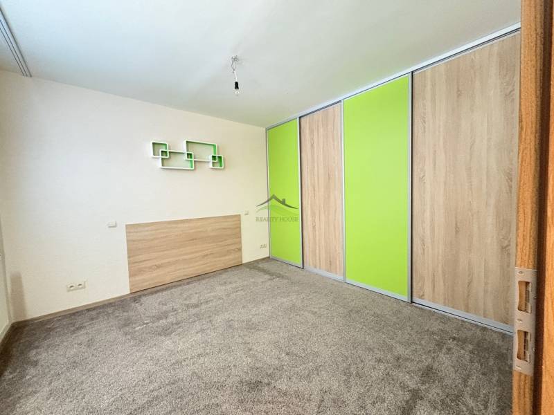 A room in a 3-room apartment with carpeted flooring and a built-in wardrobe with green sliding doors.