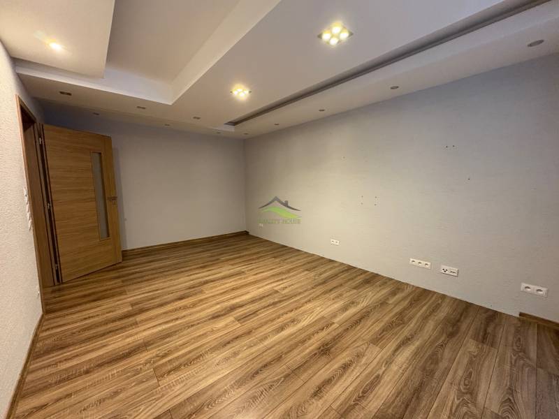 An empty room with wood-patterned flooring, white walls, and lighting in a 3-room apartment.
